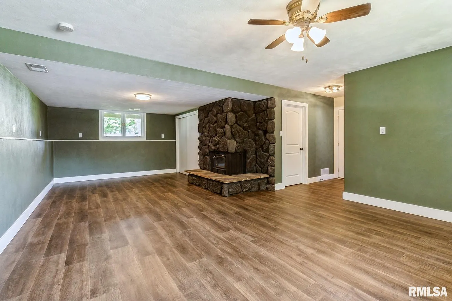 Finished basement with stone fireplace and hardwood floors